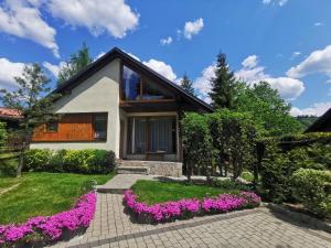 a house with purple flowers in front of it at Domek na szlaku Rysianka Beskidy in Złatna