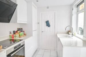 - une cuisine blanche avec un évier et une porte blanche dans l'établissement Super Stylish Flat Very Close to Freeman Hospital!, à High Heaton 16 autres photos
