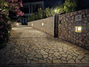 a stone path next to a stone wall at night at Villa Clio in Mánganos