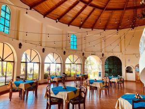 a dining room with tables and chairs and windows at Hotel Delfin Playa Bejuco in Esterillos Este