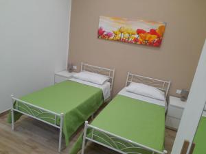 two beds in a room with a painting on the wall at Alex Home in Taranto