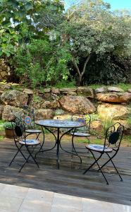 een picknicktafel en twee stoelen en een tafel en stoelen bij Alma BaHar - charming 2 bdrm house with garden עלמה בהר - דירת אירוח בלב גן פורח in Zikhron Ya‘aqov