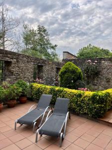 two chairs sitting on a patio next to a stone wall at Apartamentos Turisticos Paseo de la Alameda in Villaviciosa +80 photos