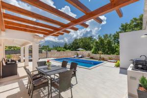 une terrasse avec une table et des chaises ainsi qu'une piscine dans l'établissement Apartment Holiday home DoMa, Čilipi near Dubrovnik, à Čilipi