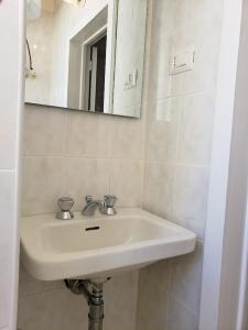 un lavandino bianco in un bagno con uno specchio di Dimora Maggi al Corso - Affitti Brevi Italia a Monte SantʼAngelo Altre 24 foto