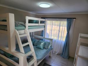 a bedroom with two bunk beds and a window at Firefinch Country Cottage in Brits