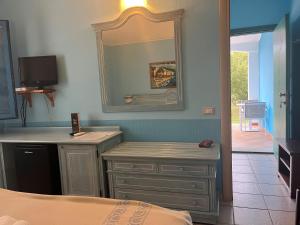a bedroom with a mirror and a dresser and a bed at Hotel Baia Cea in Bari Sardo