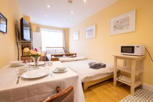 a room with a table and a bed and a tv at London VEGETARIAN Smoke & Pet Free En-suite with EV parking in Stone Grove