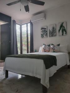 um quarto com uma grande cama branca e uma ventoinha de tecto em Casa Las Palmas em Cancún
