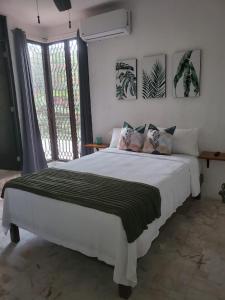 a bedroom with a large white bed and a window at Casa Las Palmas in Cancún