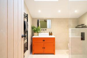 a bathroom with a orange cabinet and a sink at Spinney - a unique open plan barn, with private garden in Evesham