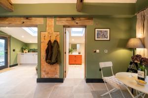 eine Küche und ein Esszimmer mit grünen Wänden in der Unterkunft Spinney - a unique open plan barn, with private garden in Evesham
