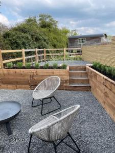 eine Terrasse mit 2 Stühlen, einem Tisch und einem Zaun in der Unterkunft Spinney - a unique open plan barn, with private garden in Evesham