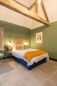 um quarto com uma cama grande e paredes verdes em Spinney - a unique open plan barn, with private garden em Evesham