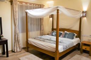 a bedroom with a four poster bed with a canopy at 3 Bedroom Luxury Villa-Sita in Diani in Kinondo