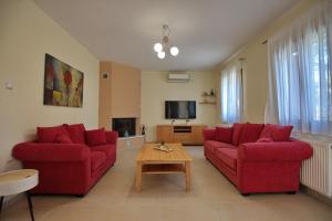 ein Wohnzimmer mit zwei roten Sofas und einem Tisch in der Unterkunft Eleni's Guest House in Alonnisos Altstadt