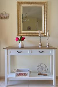 einen weißen Schminktisch mit einem Spiegel und eine Vase mit Blumen in der Unterkunft Eleni's Guest House in Alonnisos Altstadt