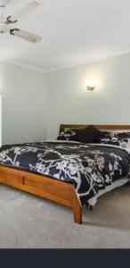 1 dormitorio con 1 cama con edredón blanco y negro en Surf Beach Bungalow, pet friendly and breakfast, en Surf Beach