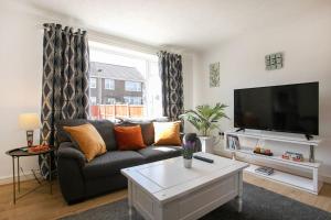 a living room with a couch and a flat screen tv at Maltby House, Rotherham, for families & contractors in Rotherham