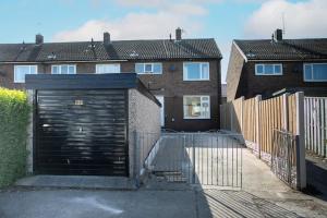 a garage with a black door in front of two houses at Maltby House, Rotherham, for families & contractors in Rotherham