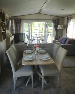a dining table and chairs in a living room at Lake Escape - Hoburne Cotswolds in South Cerney