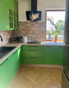 維亞特爾的住宿－Mazurska Sarenka，厨房配有绿色橱柜、水槽和窗户