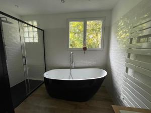 uma banheira na casa de banho com uma janela em Les jardins de l'Hermitage em Cellettes
