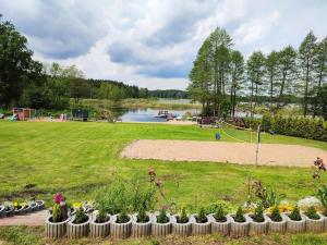a park with a pond and a playground with flowers at DOMEK NAD JEZIOREM in Żywki