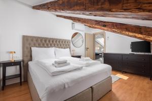 a bedroom with a large white bed and a television at Apartments Madeleine in Rijeka