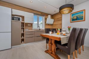 La cuisine est équipée d'une table, de chaises et d'un réfrigérateur. dans l'établissement Apartment Holiday home DoMa, Čilipi near Dubrovnik, à Čilipi