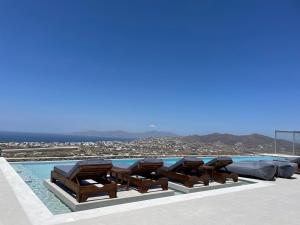 a pool with chaise lounge chairs and a swimming pool at Sunset Hill Suites in Mikonos