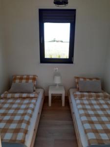 twee bedden in een kamer met een raam en een tafel bij Złotopolska Sielanka 