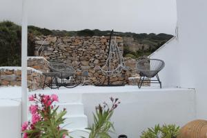two chairs sitting on a ledge next to a stone wall at Cycladic Villa in Amorgos Island (Maison Shiro) in Arkesíni