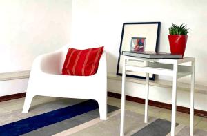 a white chair with a red pillow next to a side table at APPARTAMENTO SFERISTERIO in Macerata