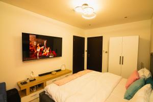 ein Schlafzimmer mit einem Bett und einem TV an der Wand in der Unterkunft Piano and Gold at The Signature, Tetteh Quarshie in Accra