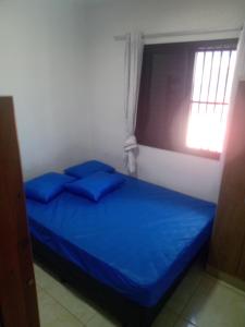 łóżko z niebieskimi poduszkami w pokoju z oknem w obiekcie Ed.fragatas residence w mieście Bertioga