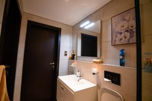 a bathroom with a sink and a toilet and a mirror at Piano and Gold at The Signature, Tetteh Quarshie in Accra