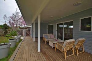 un porche con sillas y una mesa en una casa en Magnolia Cottage en Coffs Harbour