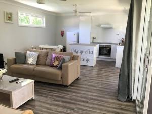 a living room with a couch and a kitchen at Magnolia Cottage in Coffs Harbour