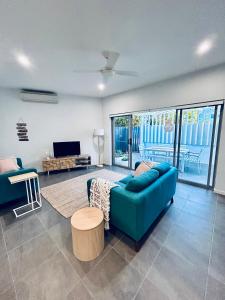uma sala de estar com um sofá azul e uma televisão em Unit 1 - Manly Boutique Apartments em Brisbane
