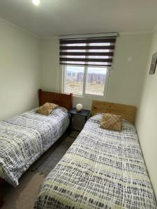 two beds in a room with a window at Dpto Full Equipado ,6 Pers ,2 Baños + Estacionamiento in Puerto Montt