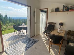 a living room with a sliding glass door with a table and chairs at Cozy forest cabin with amazing mountain view in Torsby