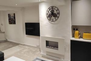a living room with a fireplace and a clock on the wall at Cosy 1 Bedroom Flat in Southam in Southam