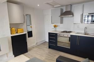 a kitchen with white and blue cabinets and a sink at Cosy 1 Bedroom Flat in Southam in Southam