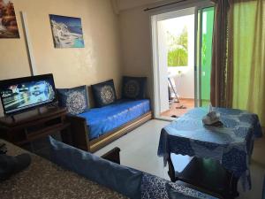 een woonkamer met een blauwe bank en een tv bij Perle sur la mer in Mohammedia