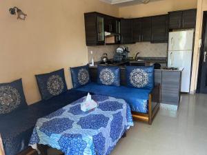 ein Wohnzimmer mit einem blauen Bett und eine Küche in der Unterkunft Perle sur la mer in Mohammedia