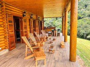 una veranda con sedie e tavoli in una baita di tronchi di As 3 Casinhas no Paraiso em Cunha!! a Cunha
