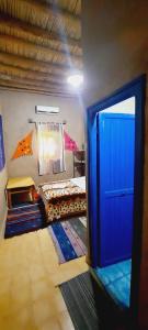 a room with two beds and a blue door at Hôtel Riad Tadarte Familier in Merzouga