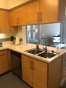a kitchen with a sink and wooden cabinets at The Palomino - Modern, Stylish, Secure Entry, Spacious Condo with 2 Master Bedrooms, WLK to Pier in Los Angeles