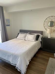a bedroom with a large bed with white sheets and a lamp at The Palomino - Modern, Stylish, Secure Entry, Spacious Condo with 2 Master Bedrooms, WLK to Pier in Los Angeles